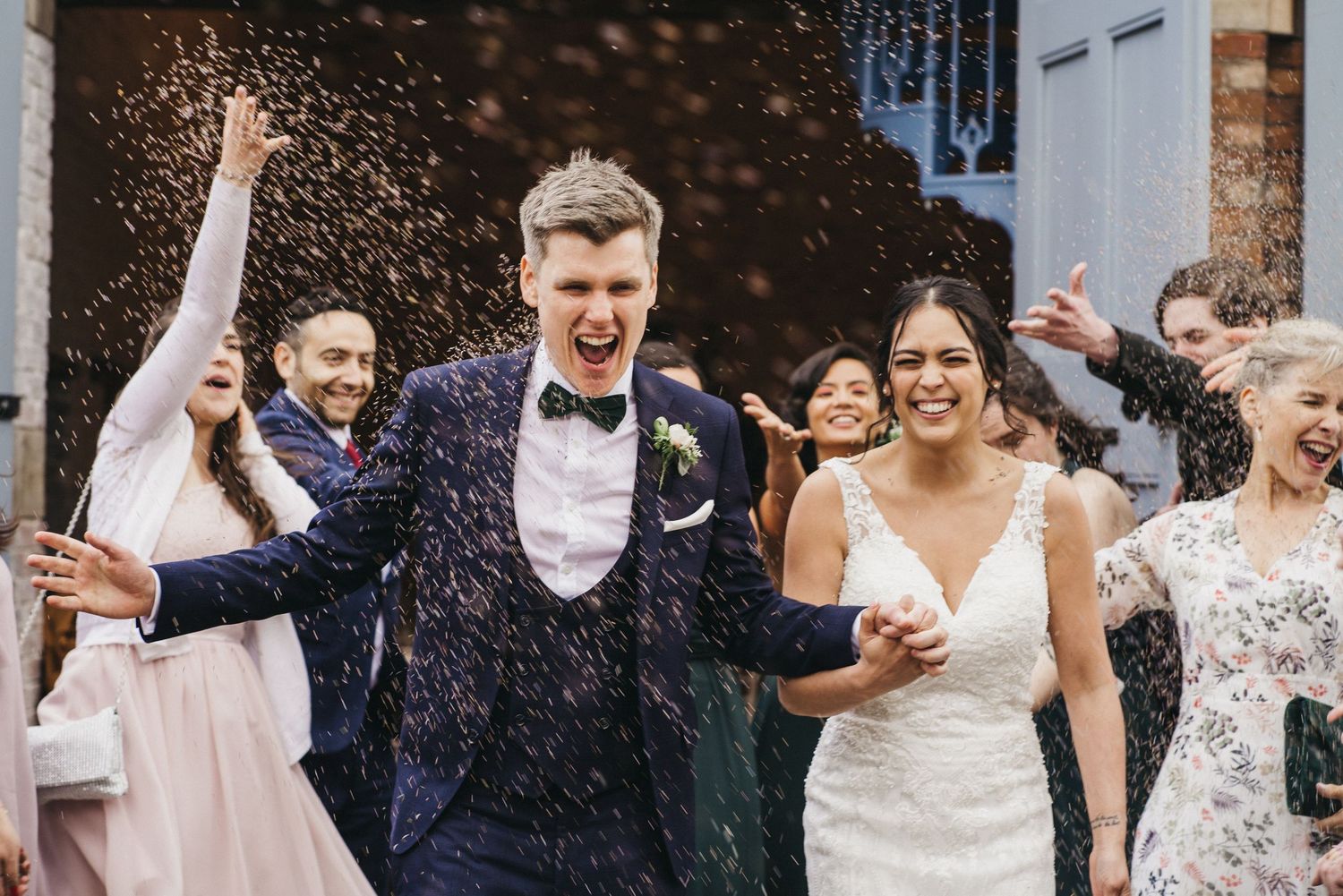 Wedding guests celebrate with confetti on a joyous day, showering the newlyweds in a festive outdoor scene.