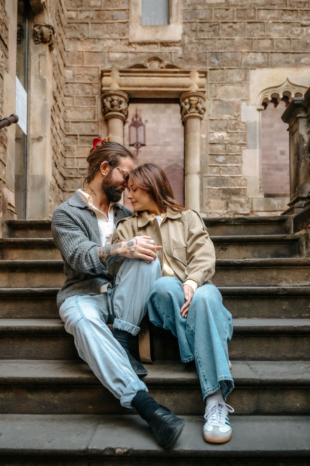 Intimate side shot of them standing close near a wooden door.