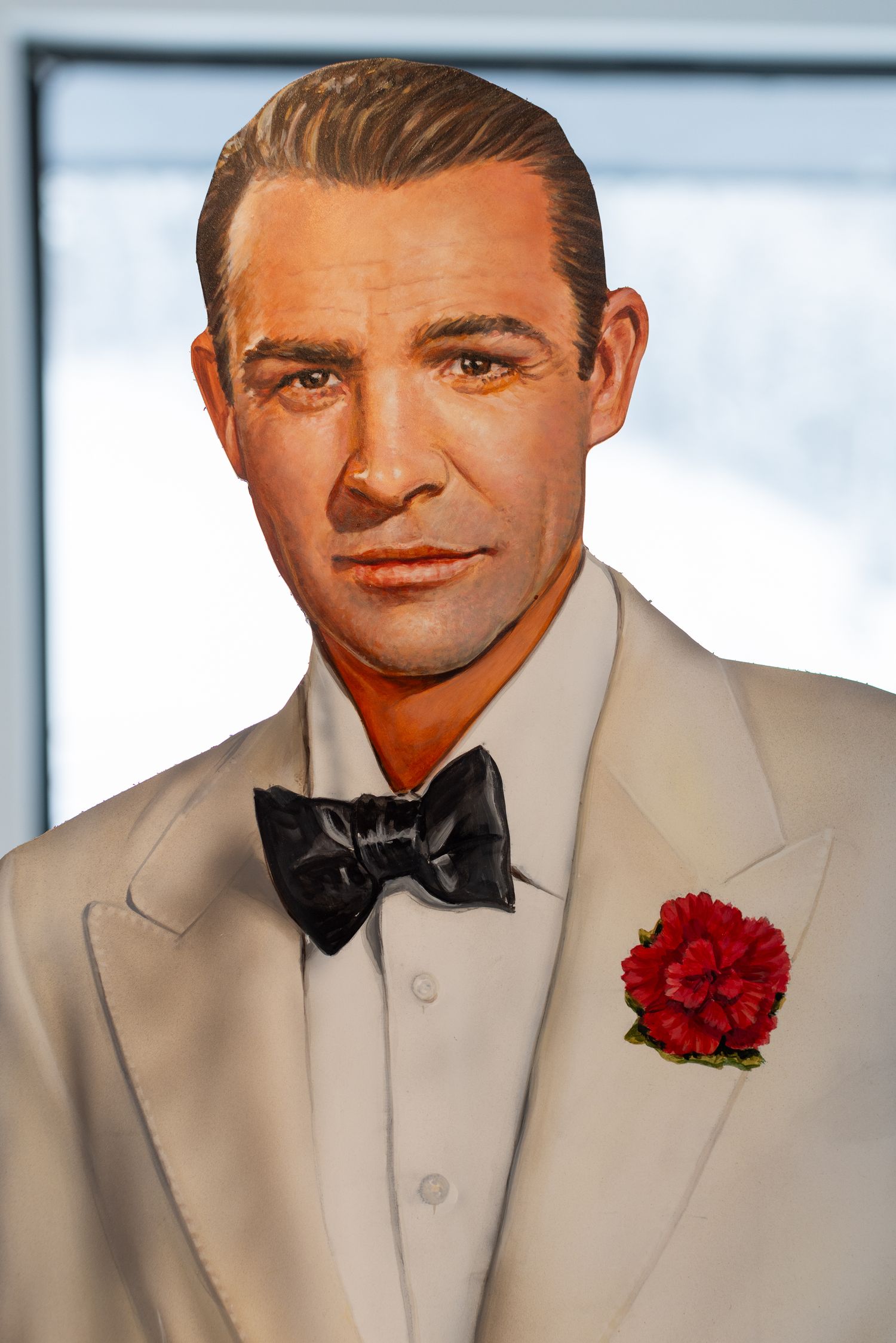 Portrait of a gentleman wearing a white dinner jacket with black bow tie and red carnation boutonniere.