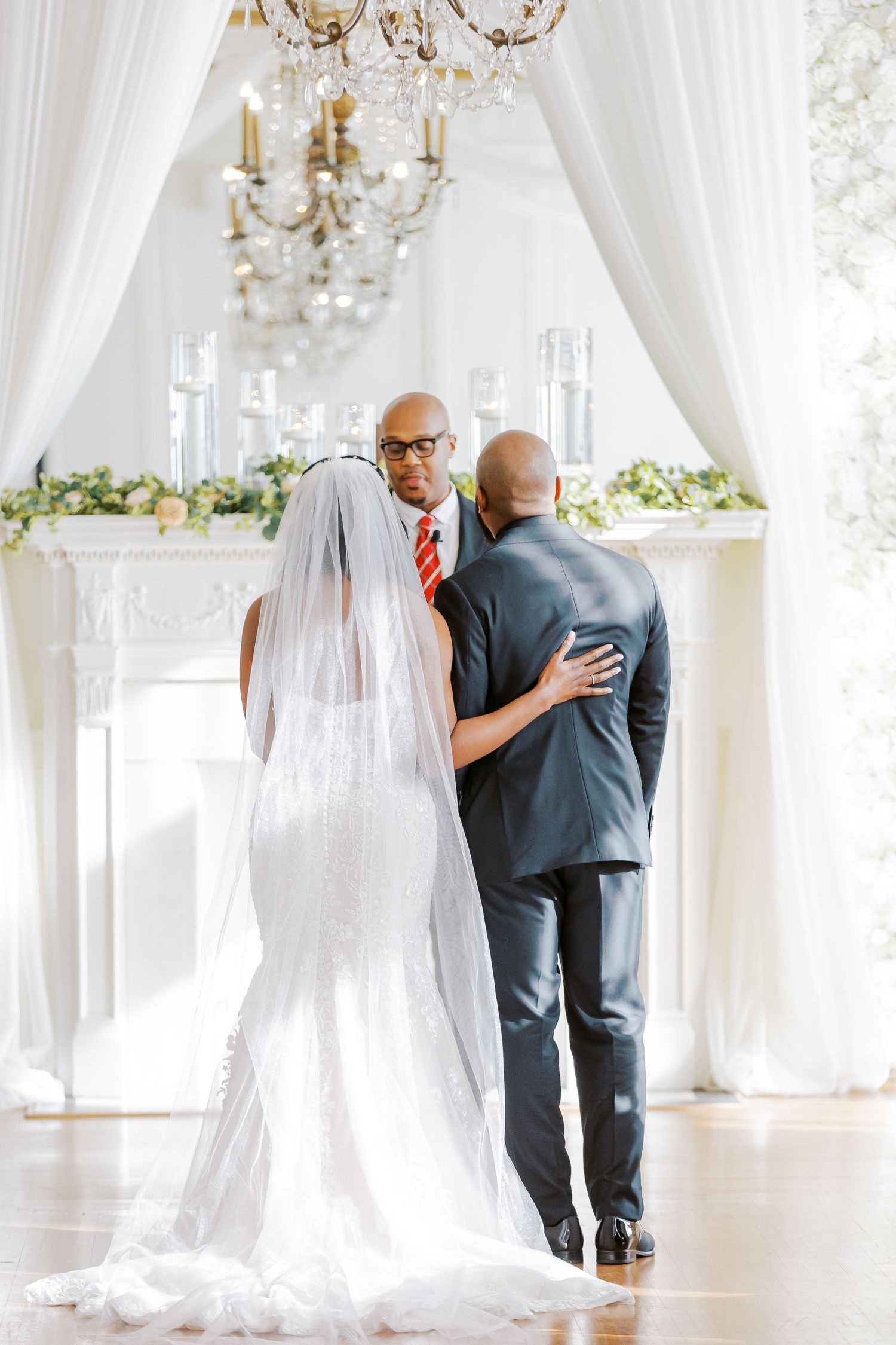 Wedding ceremony setting with crystal chandeliers and white drapery creating an elegant backdrop.