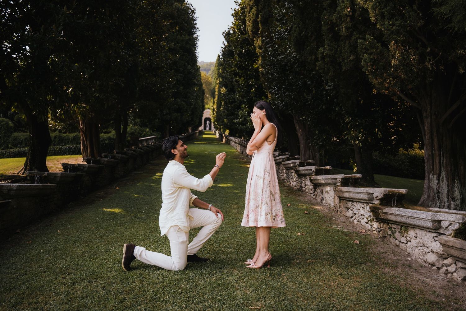 Garden marriage proposal moment captured in romantic outdoor setting.