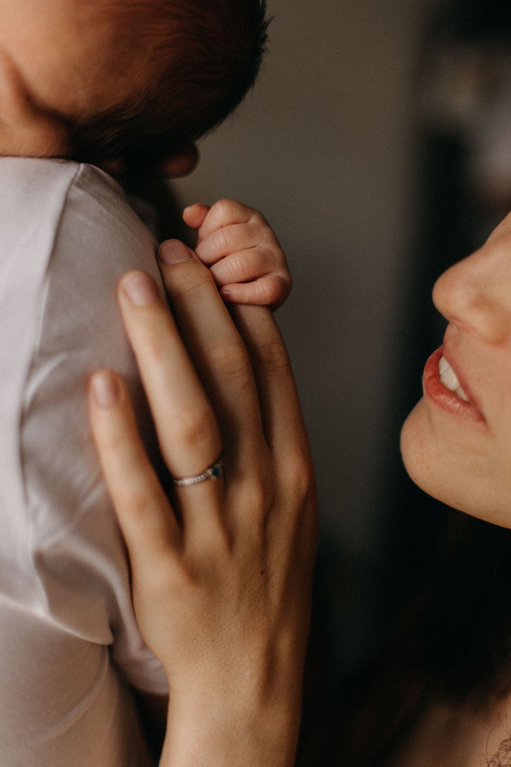 Close-up shot of tender moment between couple with baby showing wedding ring detail.