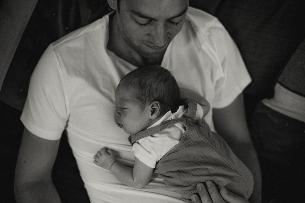 A tender black and white photograph showing a parent cradling a sleeping infant in a peaceful embrace.