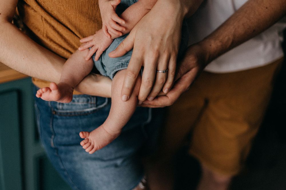 Close-up view of tiny baby feet and adult hands holding them tenderly in a nurturing family moment.