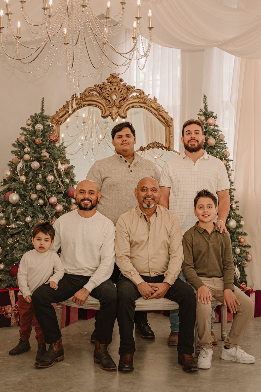 Multi-generational family holiday portrait with decorated Christmas trees and ornate mirror.
