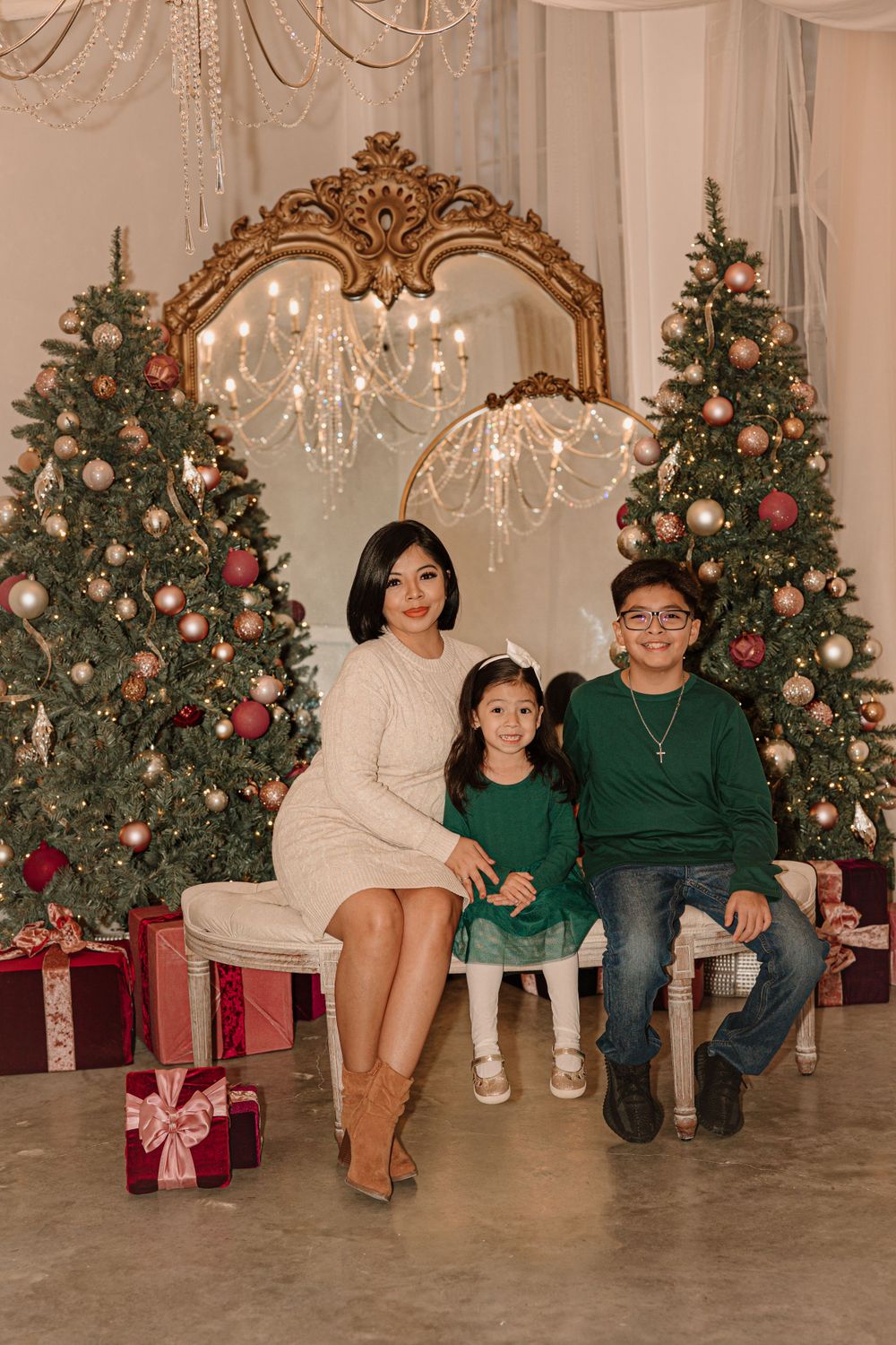 Festive Christmas photo backdrop with two decorated trees, gold mirror and wrapped presents.