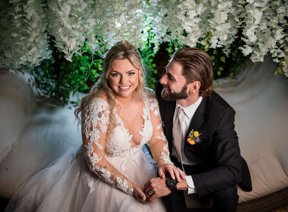 A tender wedding moment captured against a backdrop of white floral decorations and green accents.