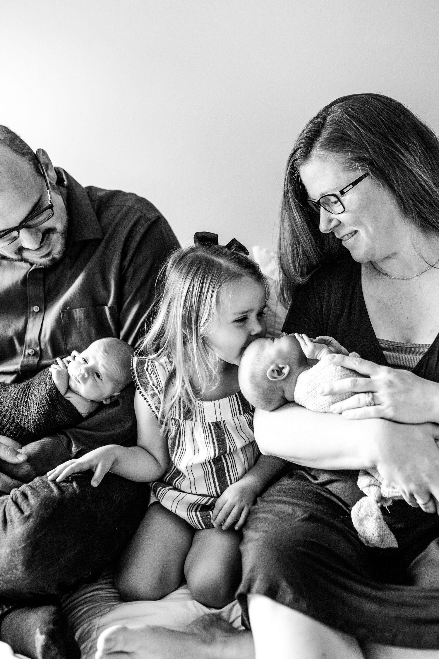 Black and white portrait of a family sharing joyful moments together on a couch.