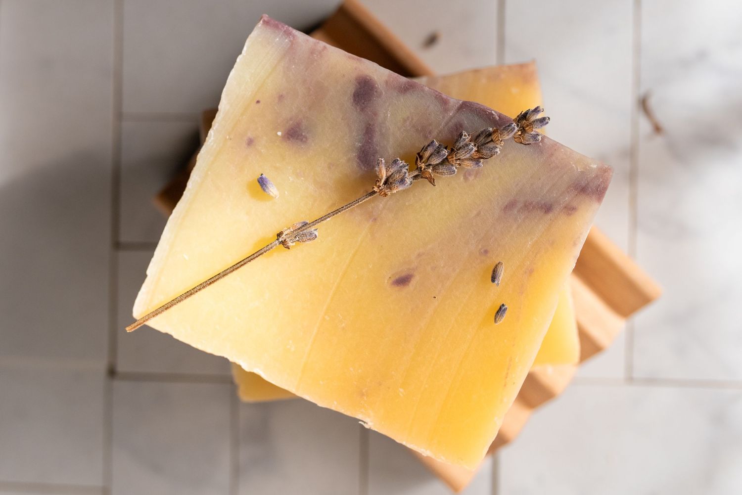 Handcrafted yellow and pink soap bars arranged on a white wooden surface.