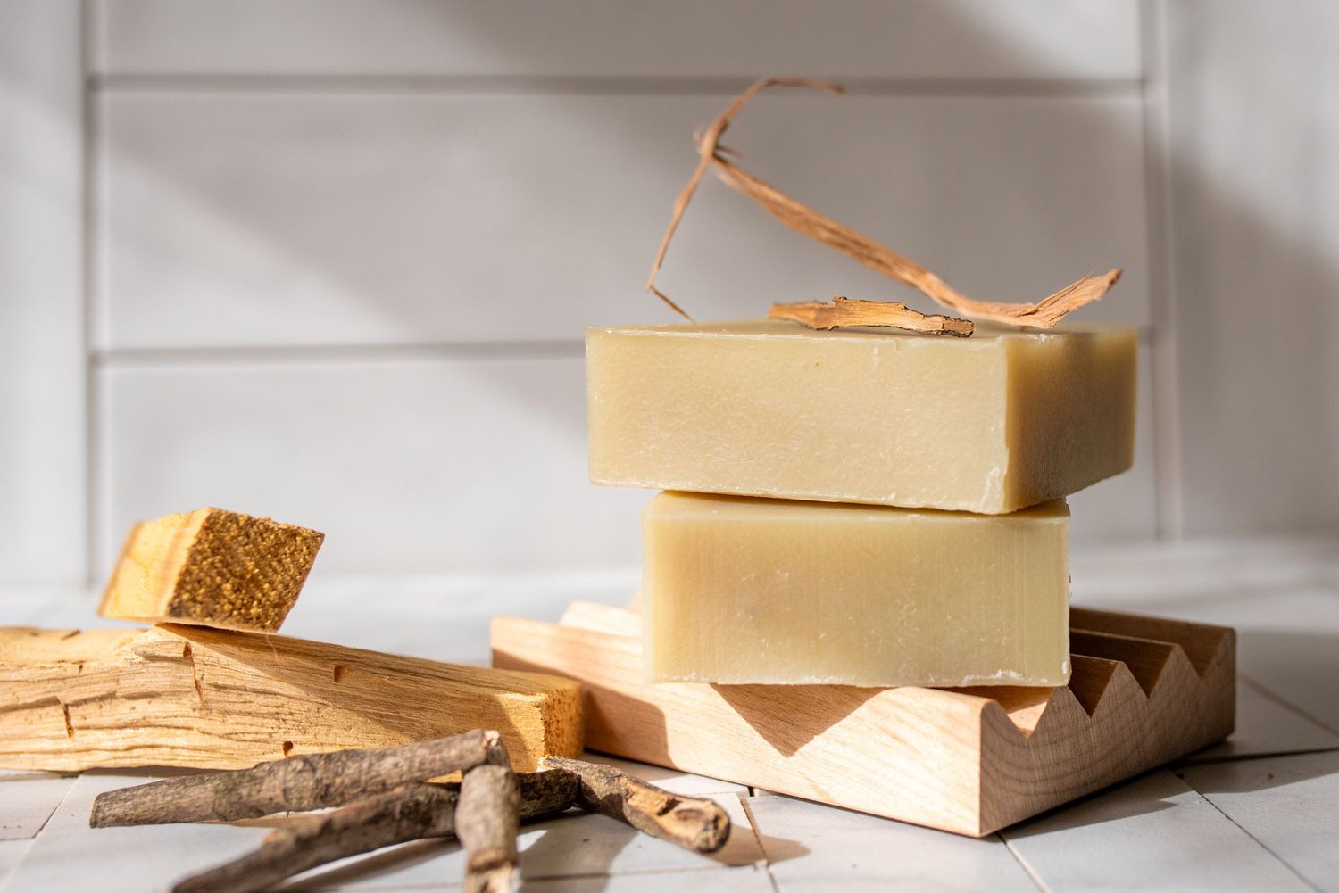 Minimalist arrangement of cream colored soap bars on white wooden surface.