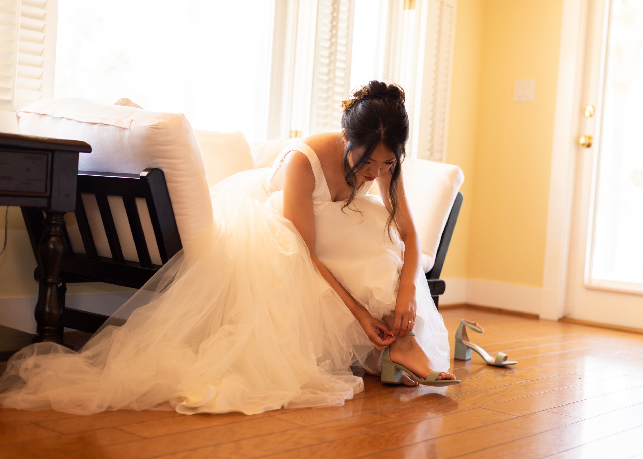 Wedding dress detail as preparations are made in sunlit room.