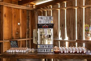 Vintage rustic barn wedding popcorn station with labeled dispensers and glass jars.
