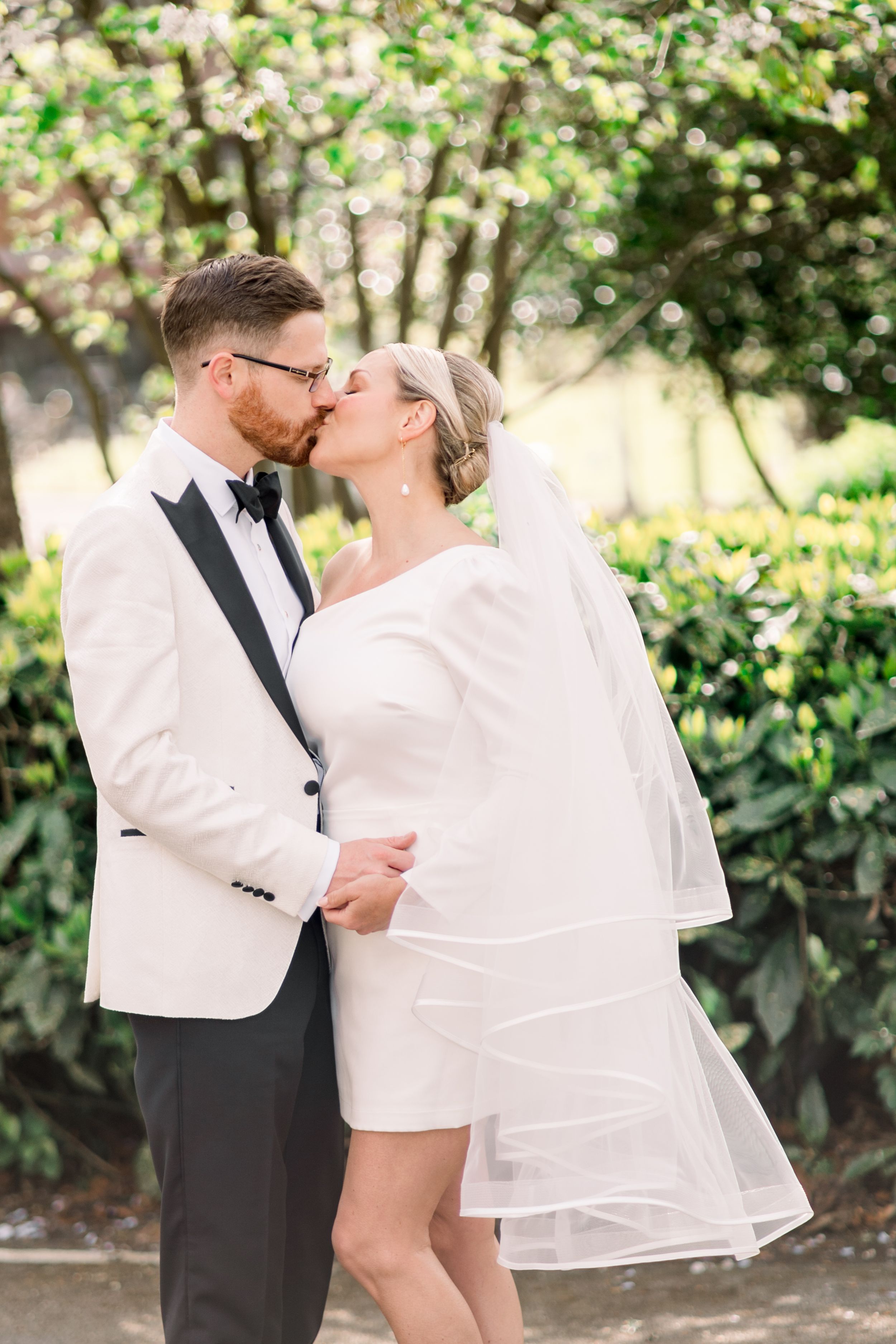 Close-up of bride and groom kissing in a spring-summer garden elopement in Nottingham Arboretum, bathed in soft natural light.