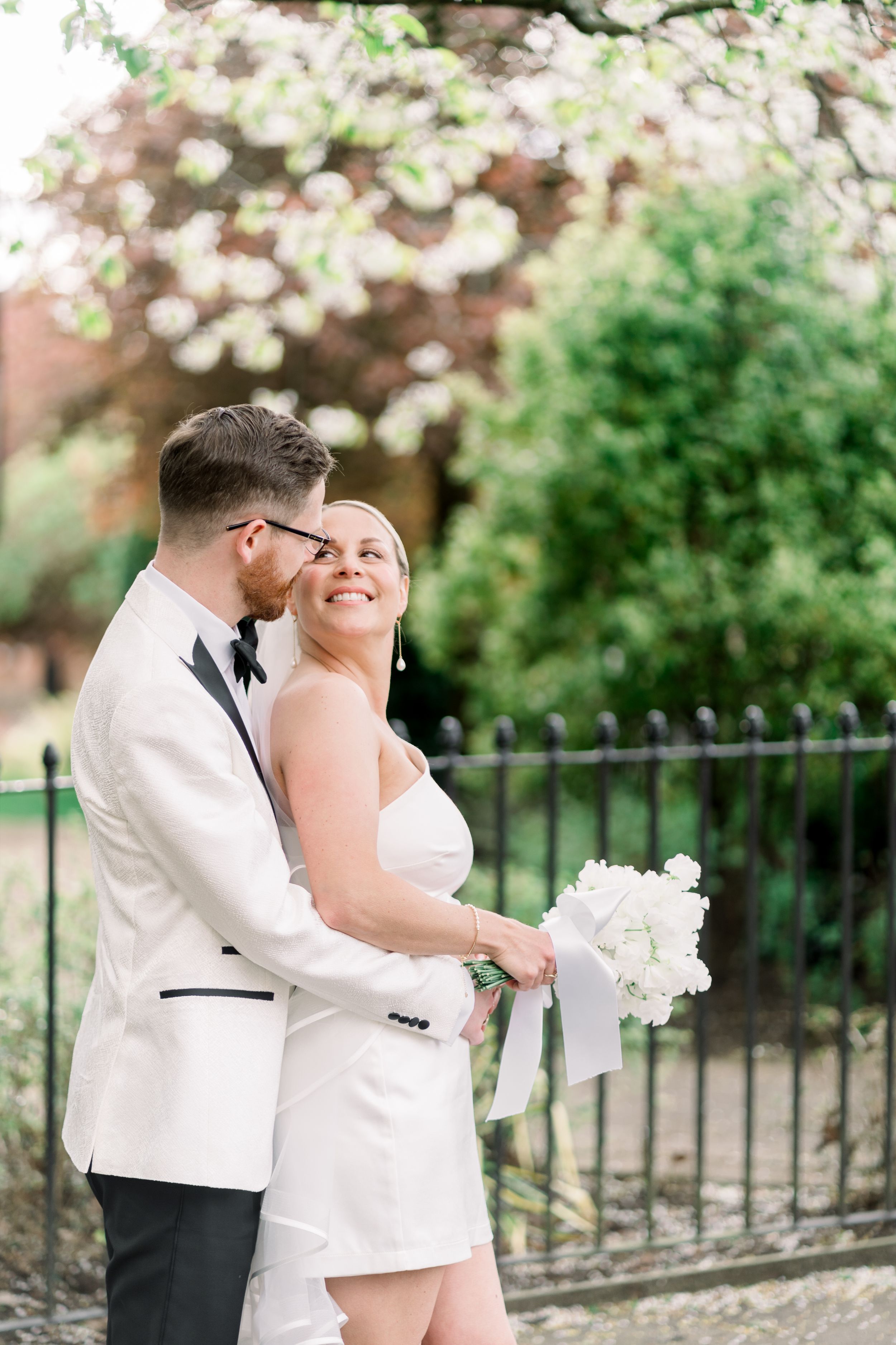Bride and groom hugging and smiling under a blossom tree in the Arboretum Park during their Nottingham spring elopement wedding.