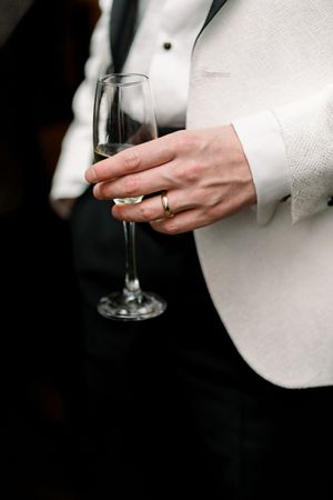 Close-up of groom holding a champagne glass, wedding ring visible, at their reception in Table 47, Lace Market, Nottingham.