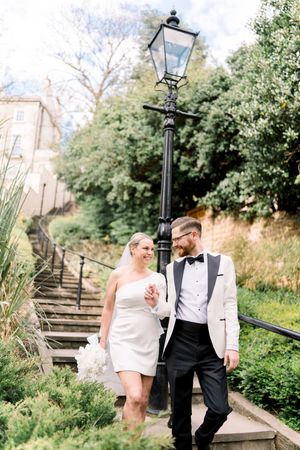 Bride and groom walking hand in hand down stone steps in The Park Estate, surrounded by greenery and historic Nottingham buildings.