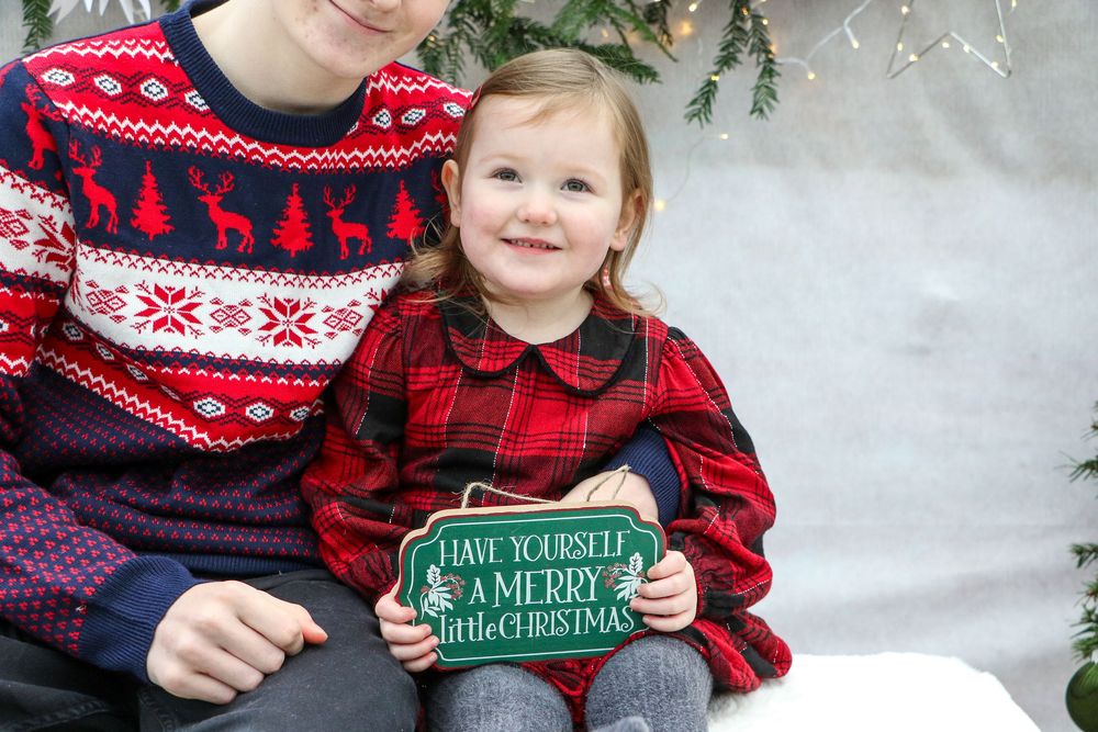 Cozy Christmas scene with matching red plaid and Nordic sweaters against evergreen decor.