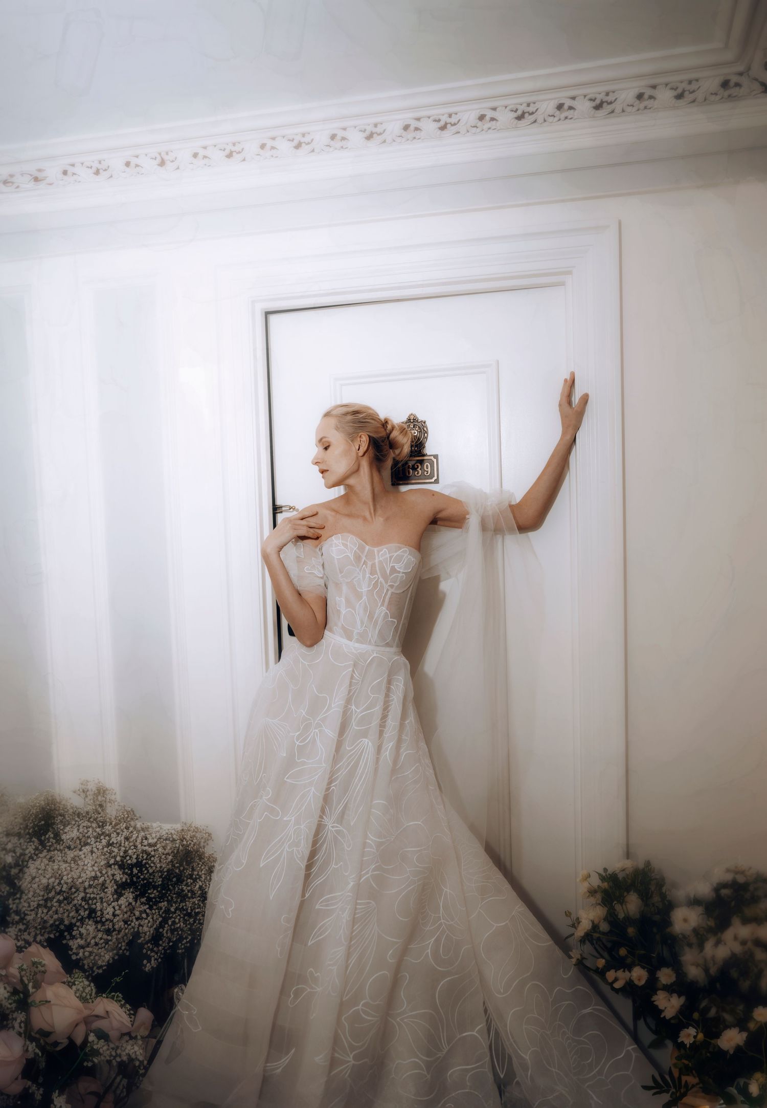Elegant bridal portrait against white wall with classic strapless wedding gown.