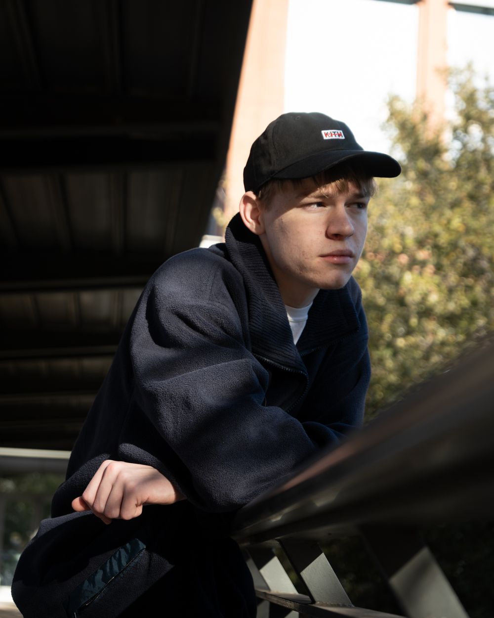 A sequence of dark silhouetted portraits in a moody lighting setting wearing a baseball cap and hoodie.
