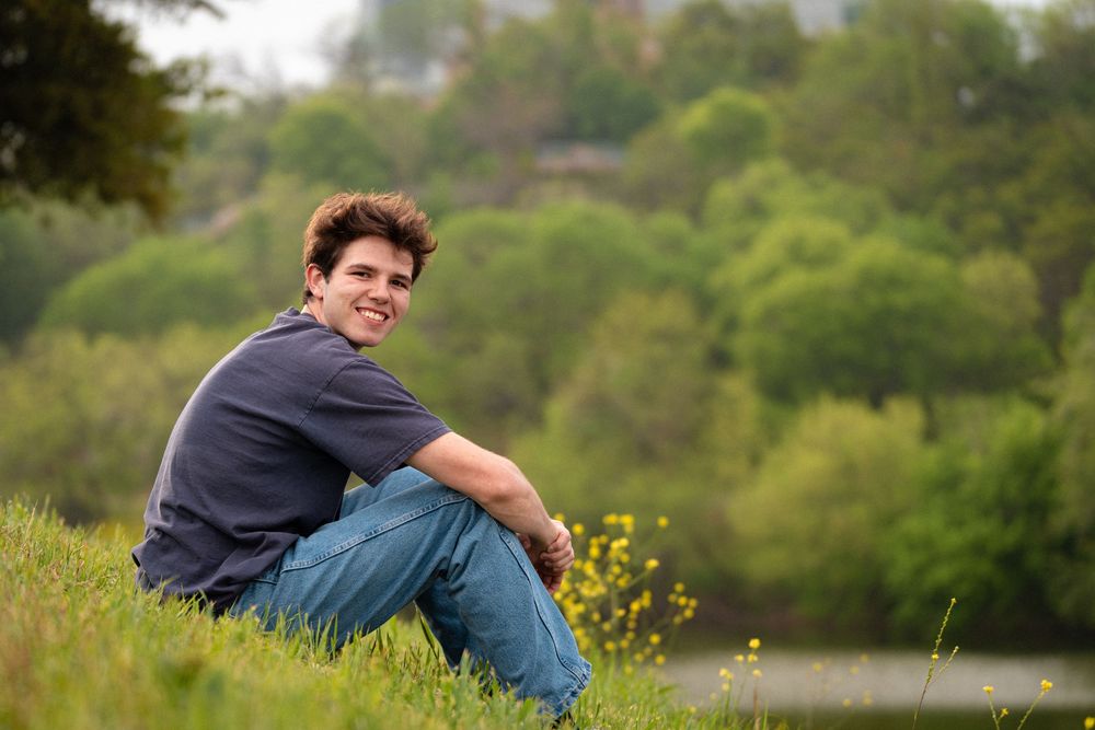 Person sitting in a grassy meadow with yellow wildflowers on a sunny summer day.