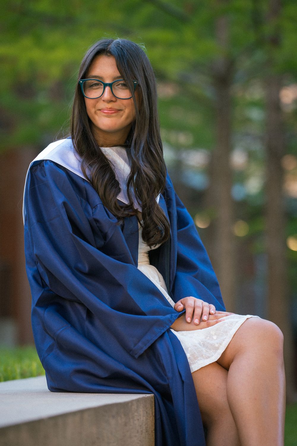 Graduation photo series showing someone in a navy blue cap and gown posed outdoors on campus.