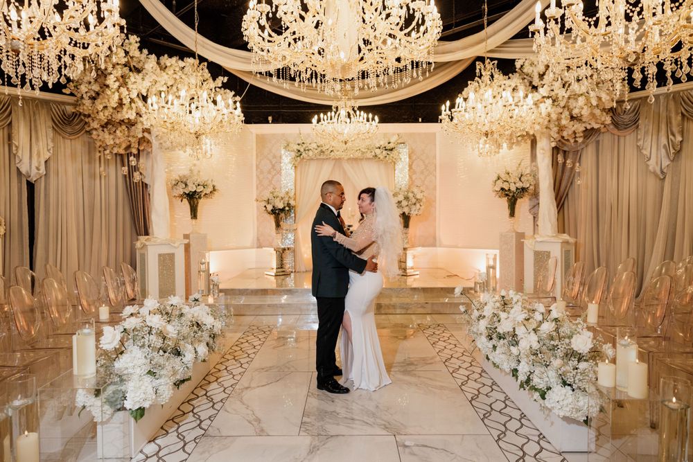 Elegant wedding ceremony setup with crystal chandeliers and white floral arrangements in an opulent ballroom.