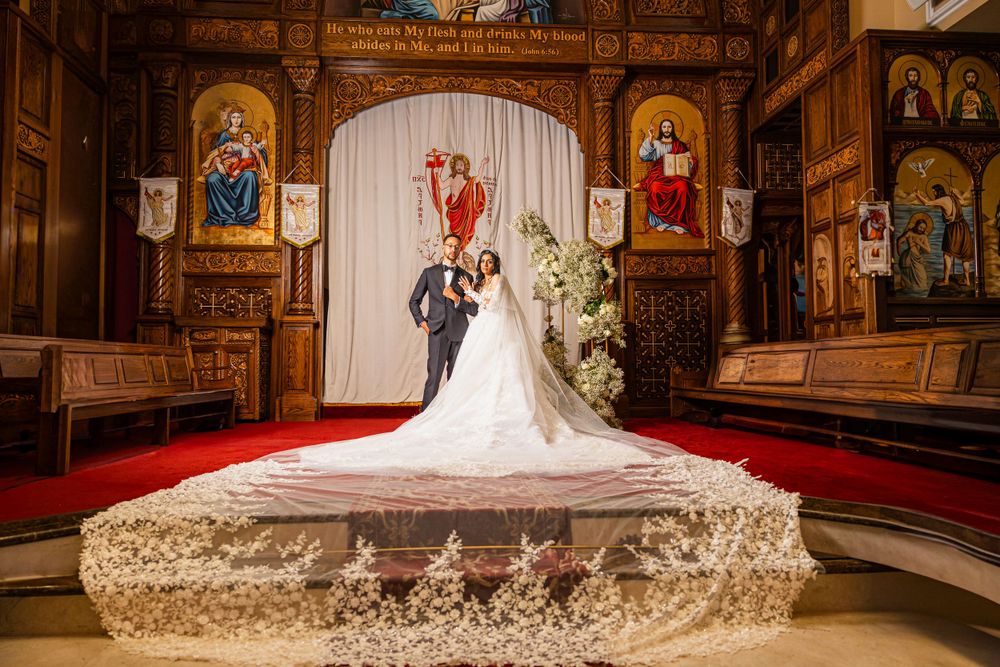A couple embraces at the altar of an ornate Orthodox church with golden icons and a dramatic red carpet for their wedding ceremony.