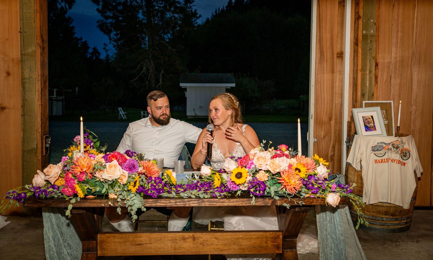Reception table decorated with vibrant floral arrangements in rustic wooden venue.