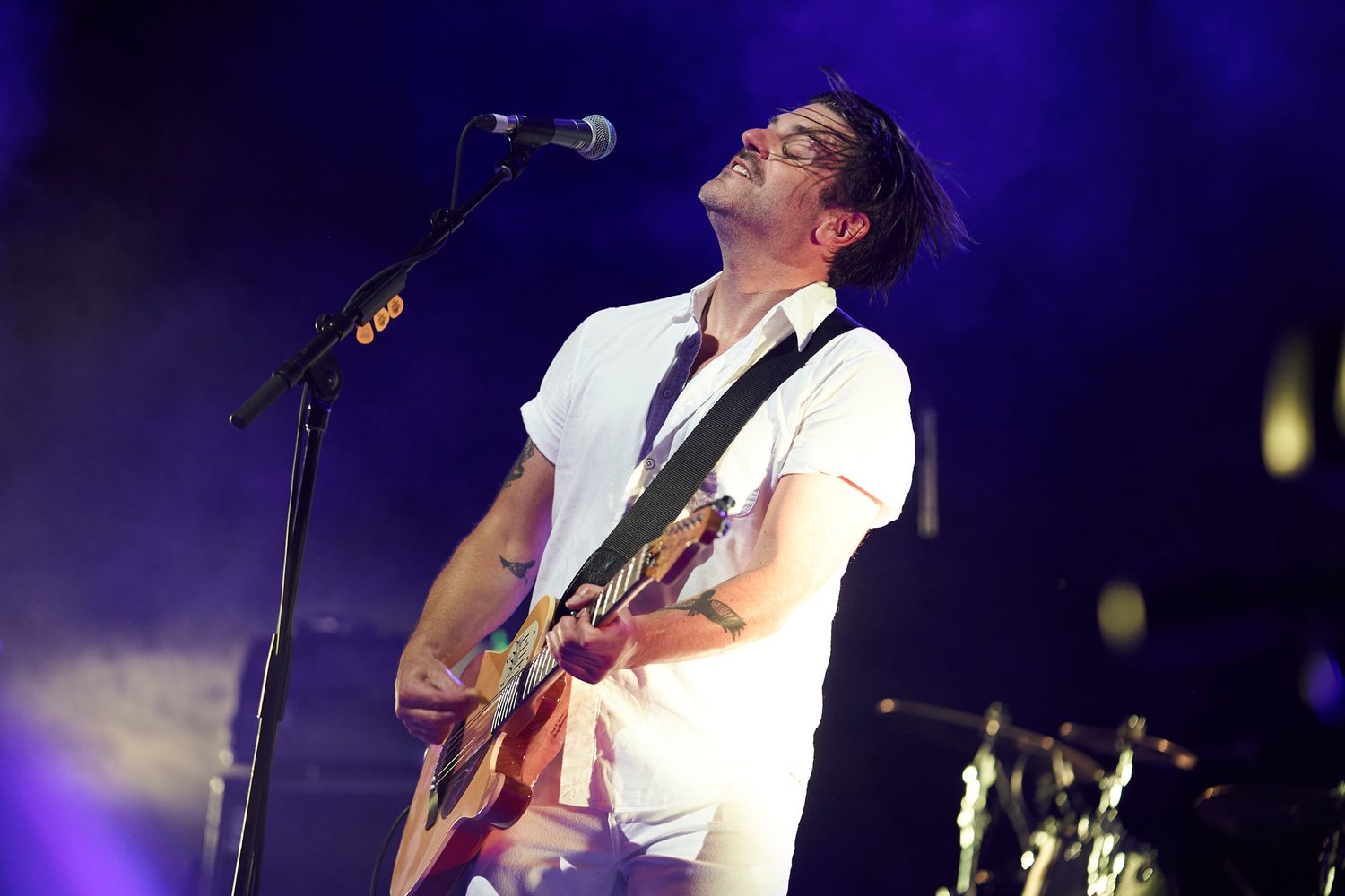 Musician performs passionately on stage at Hillside music festival in Guelph Ontario with guitar under dramatic stage lighting.