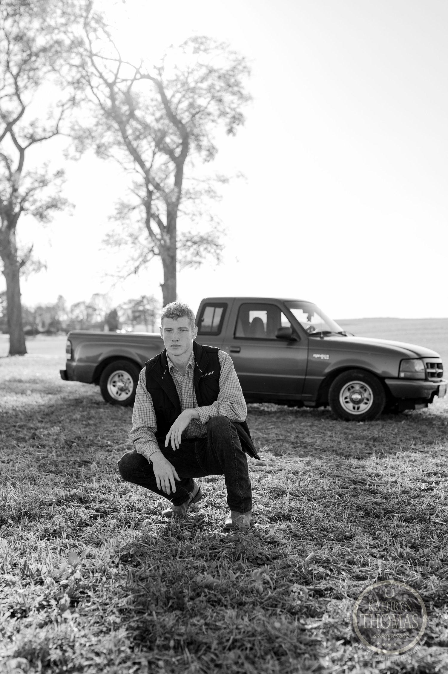 Black and white portrait with vintage pickup truck in background.