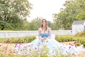 Beautiful portrait of a young lady wearing a ball gown while posed amongst flowers in a garden in Colonial Williamsburg.