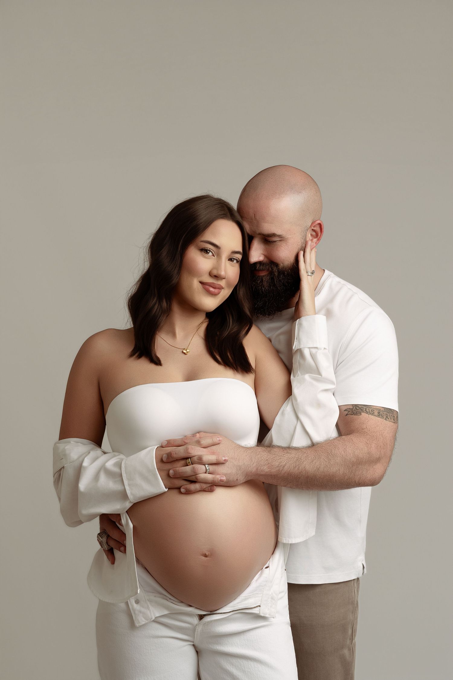 A series of minimalist maternity photos showing a couple in white against a neutral background.