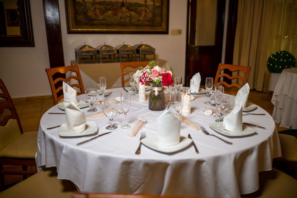 Elegant table setting with white tablecloth, fine china, and floral centerpiece in formal dining room.