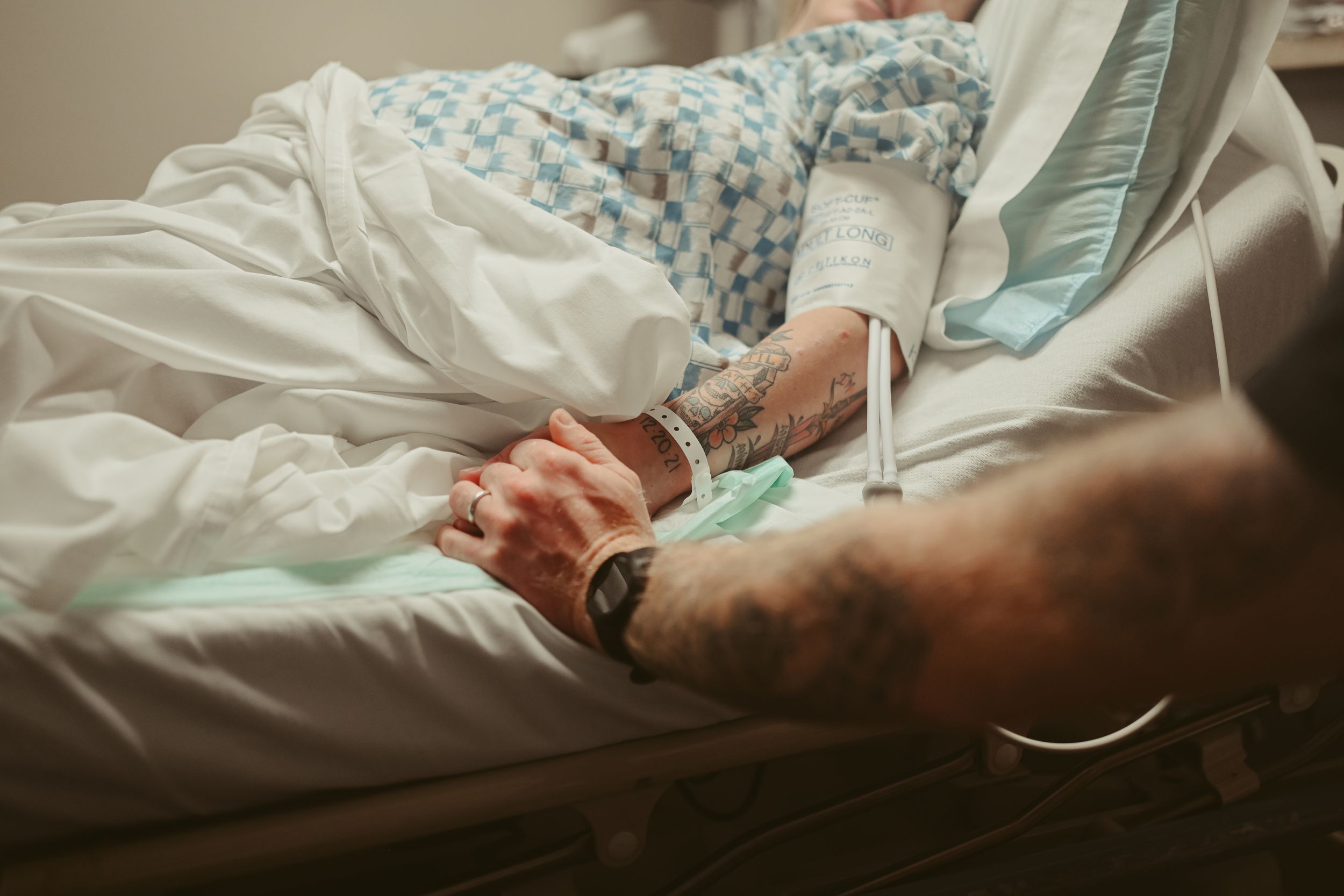 Anxious mom and dad to be hold hands in pre-op room at St. Thomas in Nashville, captured by birth photographer Disney Magic Photography.