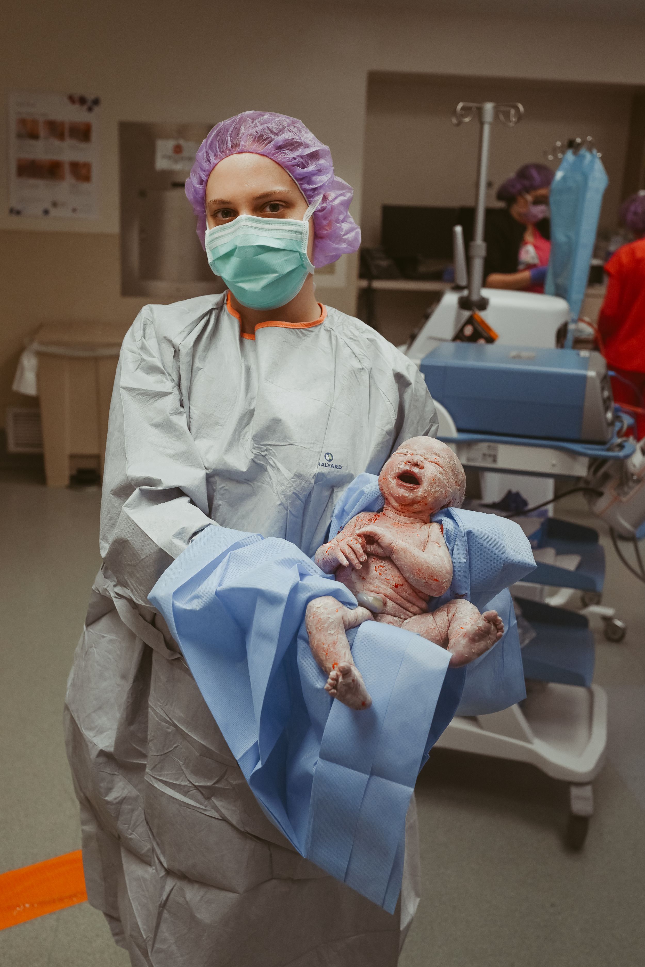 Baby girl is shown off by nurse to birth photographer in the operating room post cesarean section at St. Thomas in Nashville, Tennessee.
