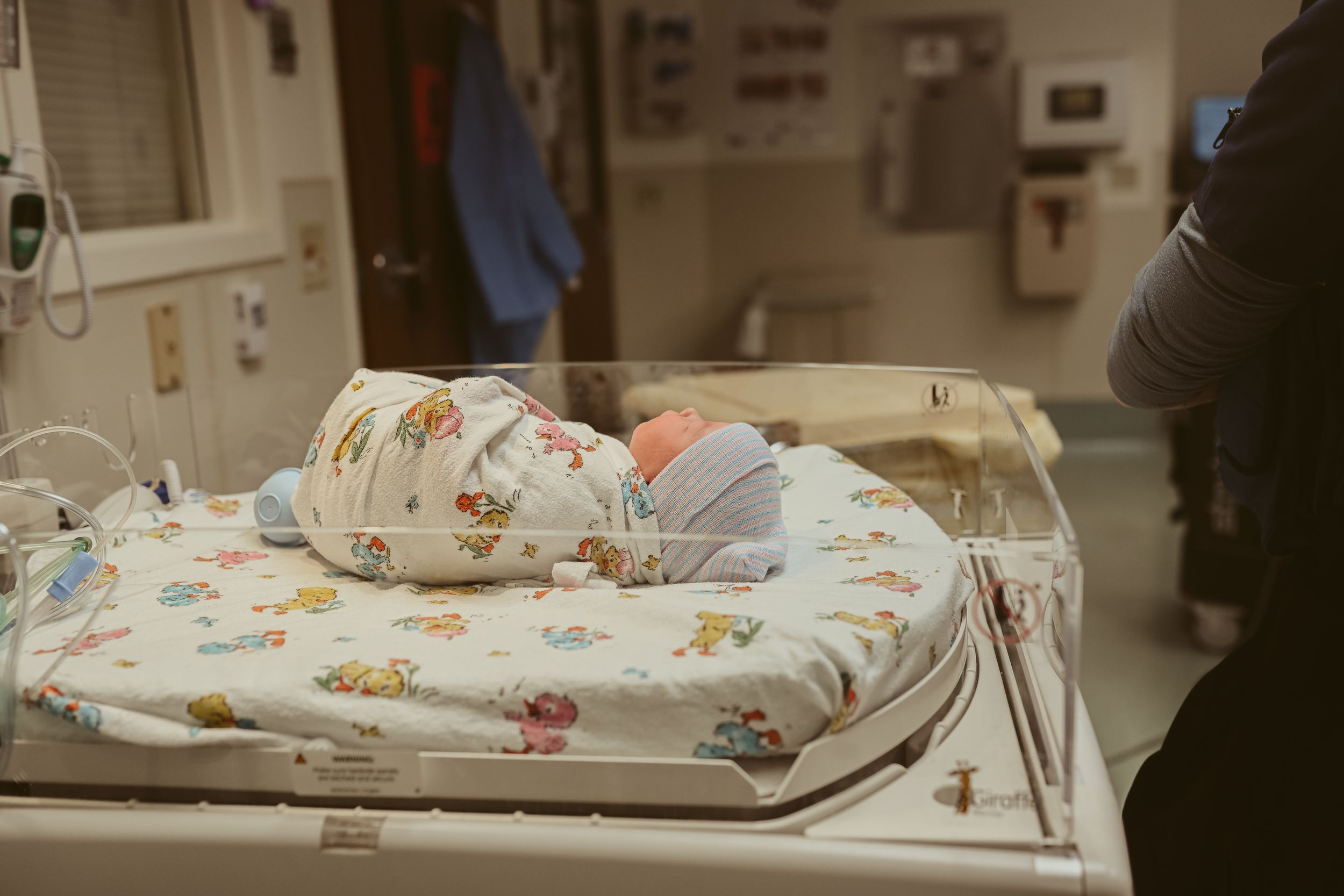 Baby girl lies in swaddle and hat in the infant warmer in the operating room post cesarean section at St. Thomas in Nashville, Tennessee.