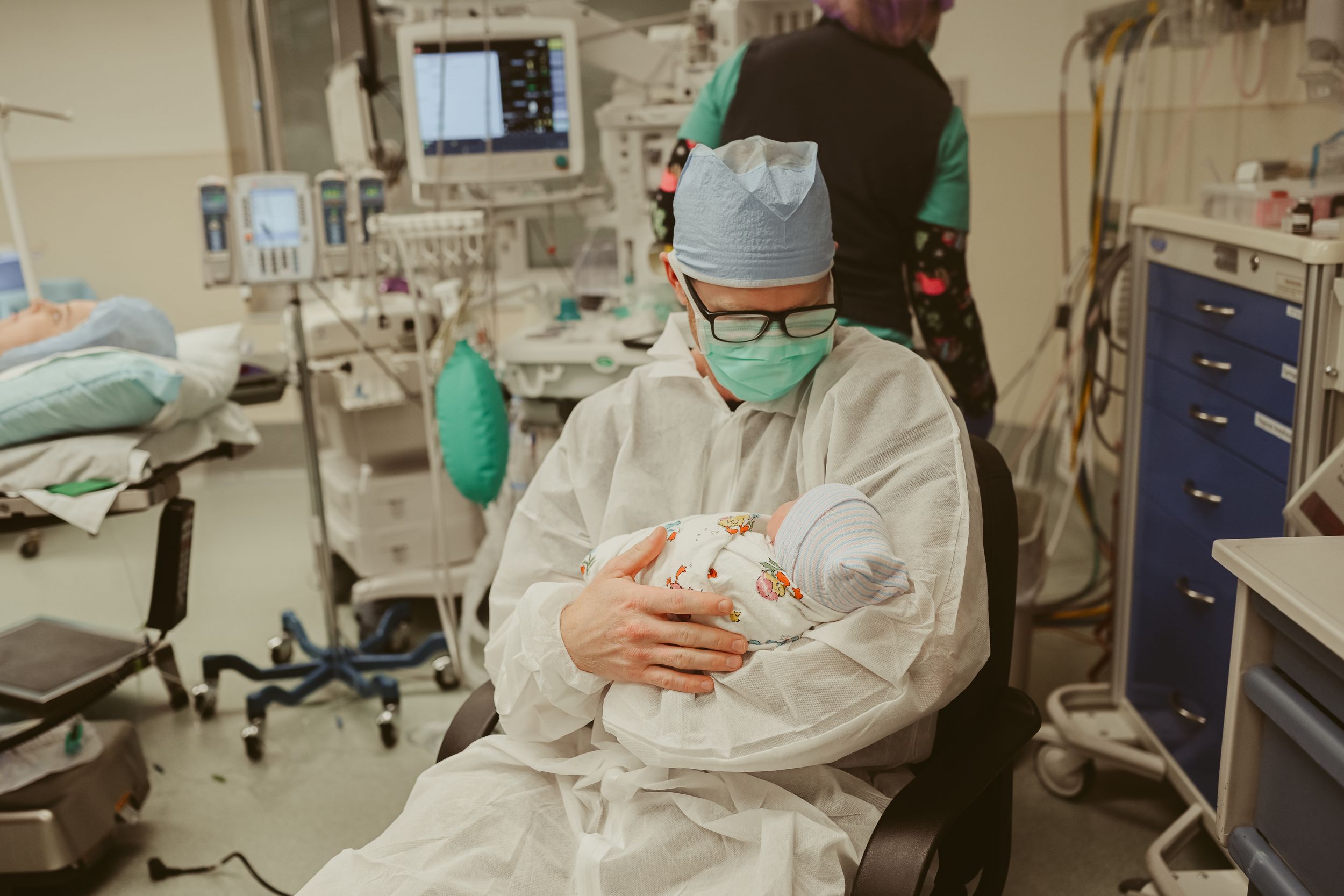 New dad holds newborn baby girl in operating room post cesarean section at St. Thomas in Nashville, Tennessee.