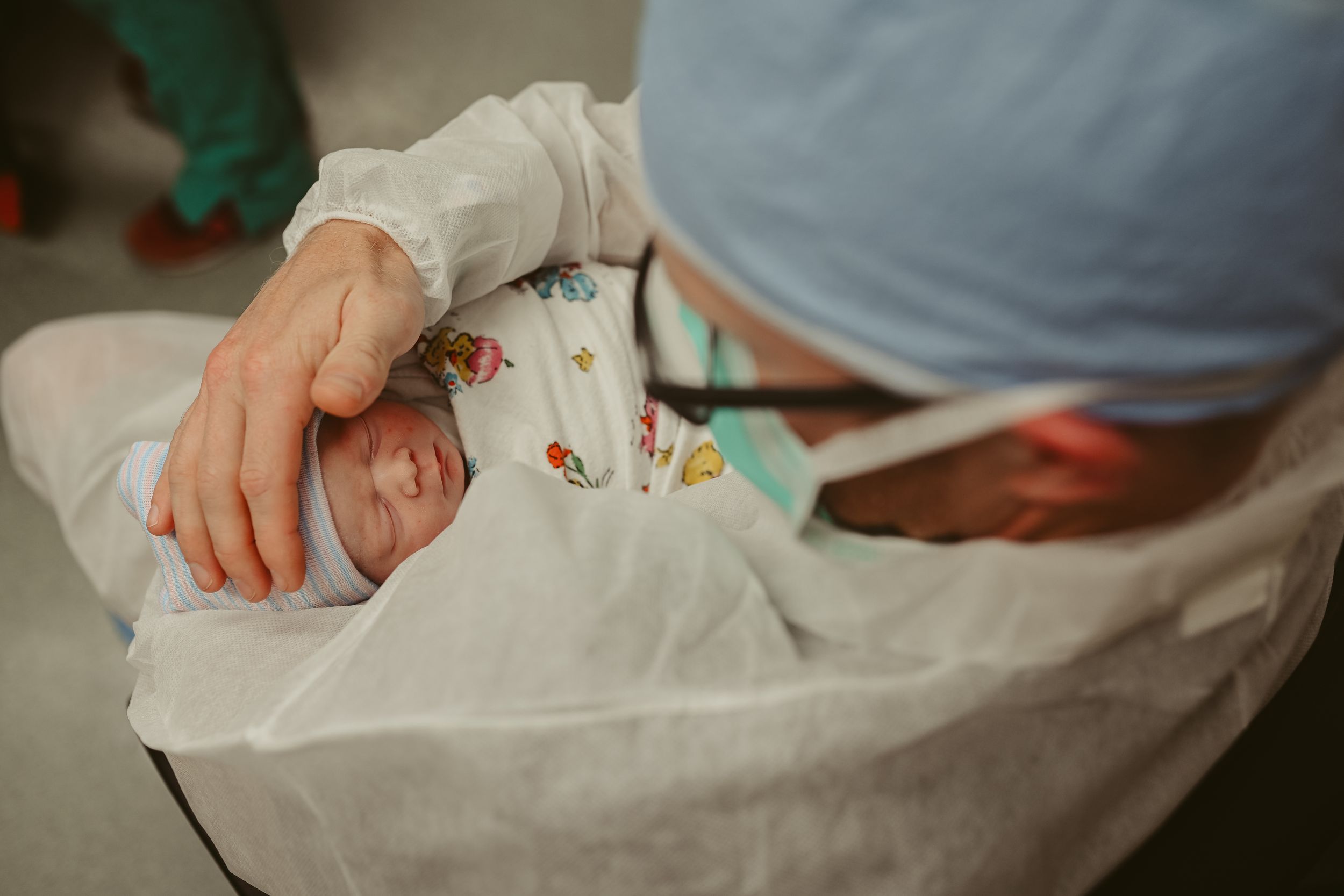 New dad caresses newborn baby girl's head in operating room post cesarean section at St. Thomas in Nashville, Tennessee.