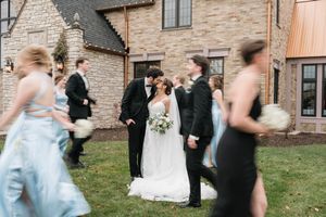 bridal party blurred as they walk past bride and groom kissing