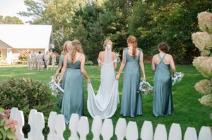 bridesmaids helping bride hold dress as they walk away