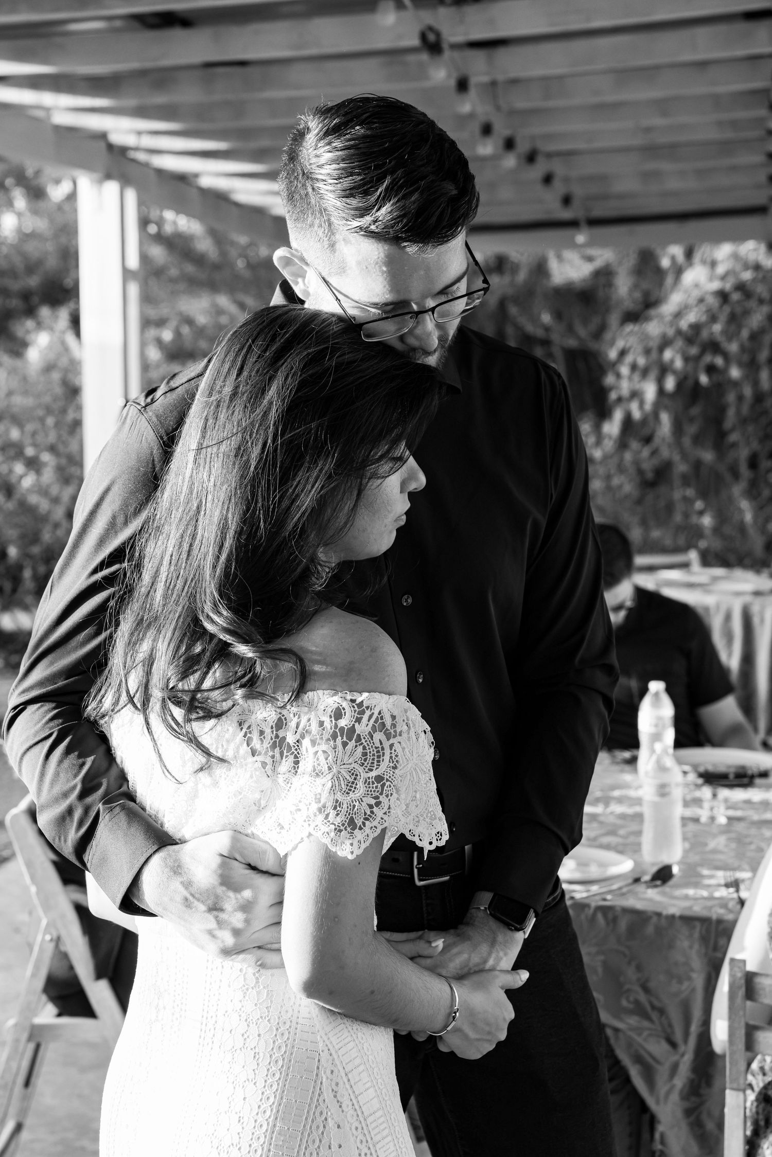 Black and white photo of a couple sharing an intimate embrace outdoors at a garden event venue.