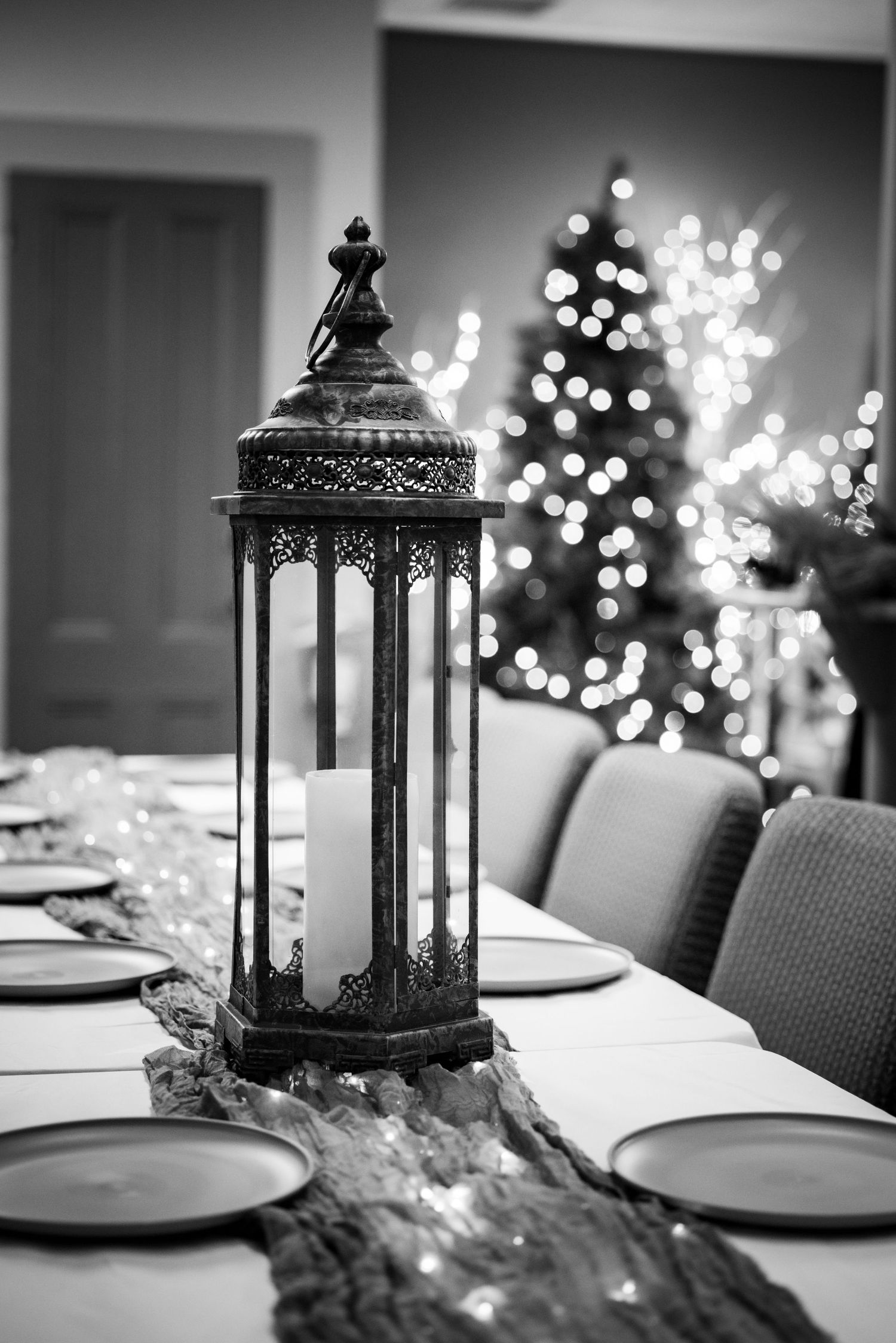 Ornate metal lantern centerpiece on a decorated wedding reception table with Christmas tree bokeh lights.