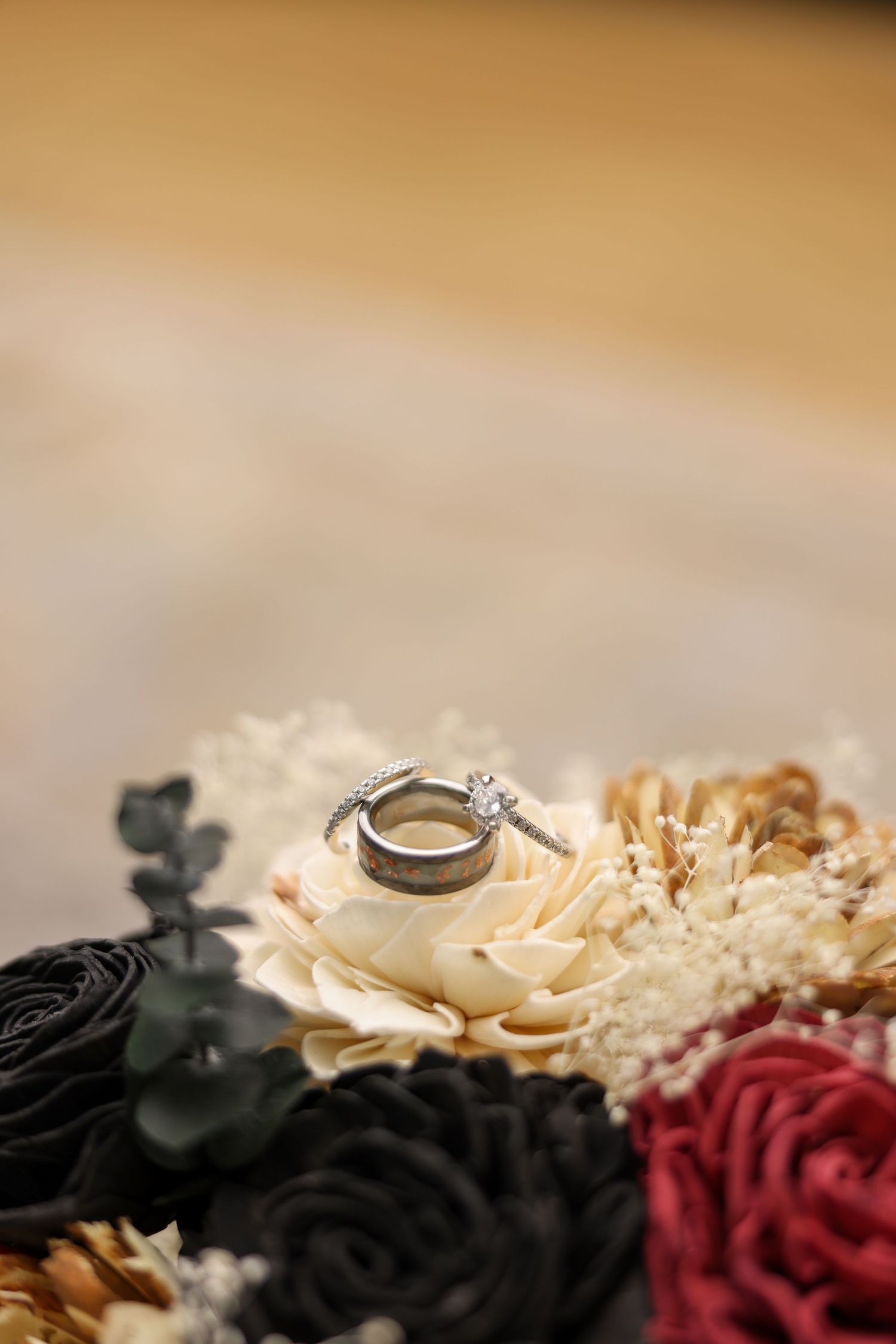 Diamond engagement ring and wedding band resting on a cream flower in a decorative bouquet.