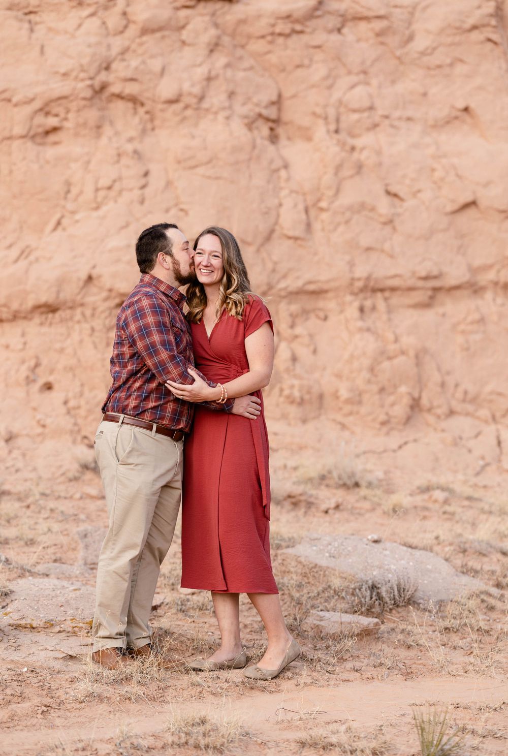 A romantic moment shared between a couple against a red rock desert backdrop.