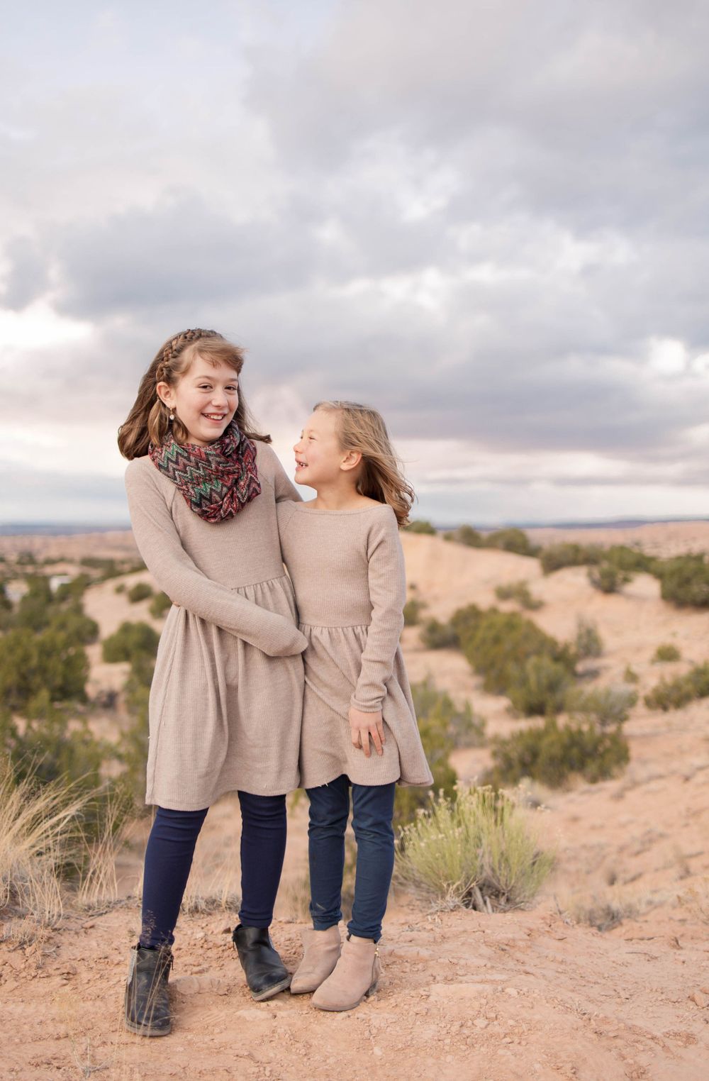 Sisters laughing in the red dirt of the New Mexican desert.