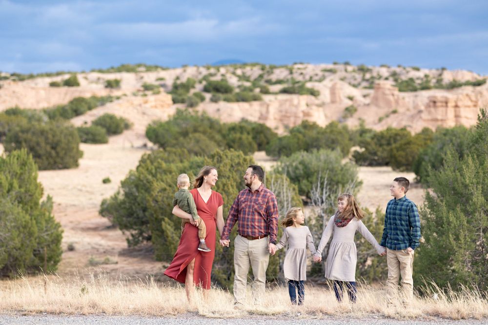 People walking together near red rock formations in a desert setting with scrub brush.