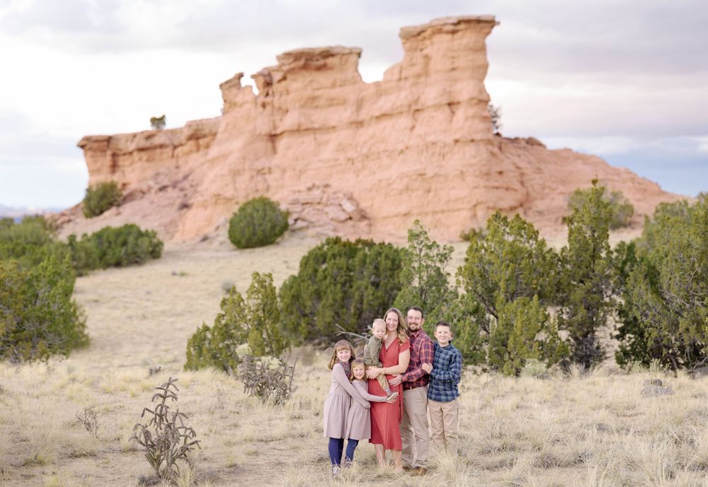 A small group poses in front of dramatic sandstone formations in the desert.