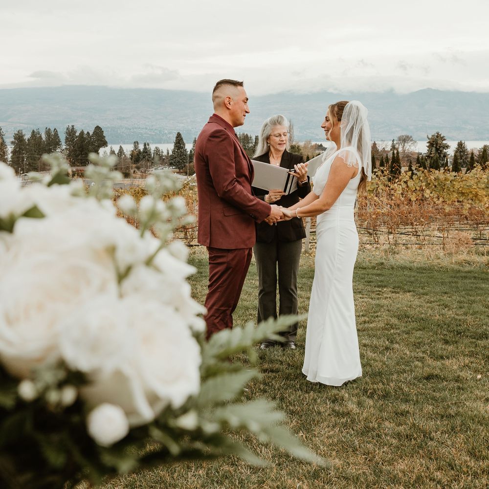 brid and groom embracing during intimate wedding in kelowna bc with pretty white flowers in foreground