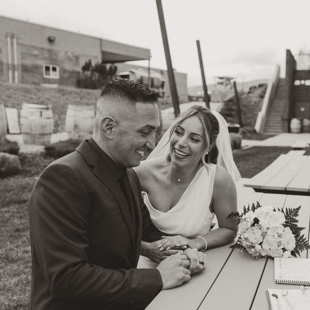 bride and groom smiling as they sign their wedding paperwork