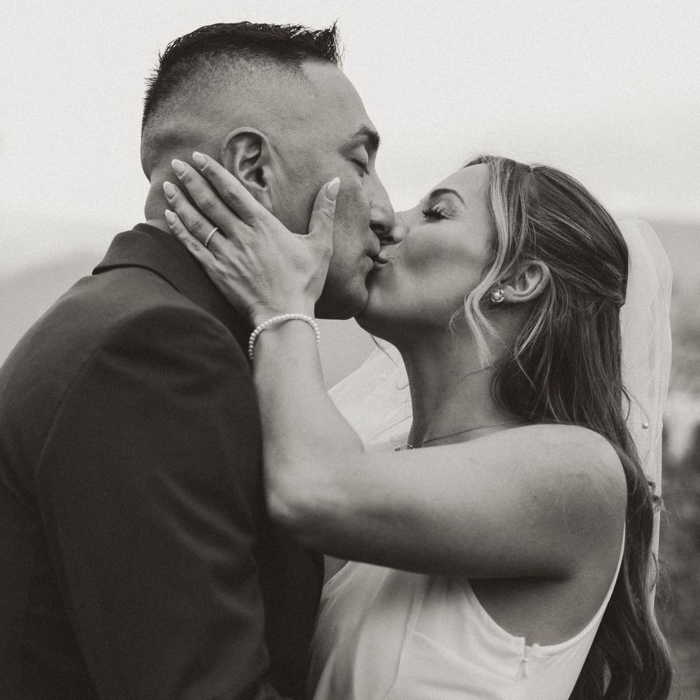 black and white candid image of bride and groom having their first kiss at kelowna wedding